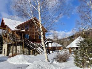 una cabaña de madera en la nieve con un árbol en Vedmid, en Ludvikuvka