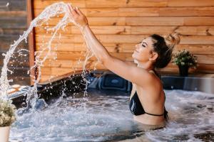 a woman in a bathing suit playing with water in a tub at Elexus Boutique in Predeal