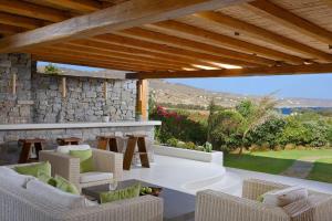 a patio with chairs and a stone wall at Beachfront Villa Kalafatis by Aesthia Estate in Kalafatis