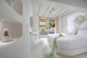 a white bedroom with a white bed and a window at Beachfront Villa Kalafatis by Aesthia Estate in Kalafatis