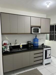 a kitchen with white cabinets and a microwave at APTO aconchegante in Manaus