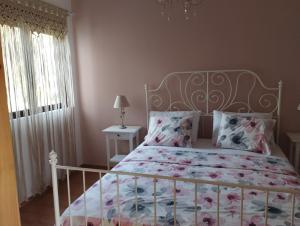 - une chambre avec un lit blanc et un couvre-lit floral dans l'établissement Olivelia, à Ixia