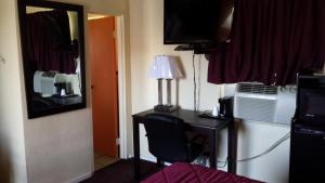 Camera dotata di scrivania con lampada e TV. di American Inn a Sedalia