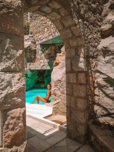 um homem sentado numa piscina numa parede de pedra em Rock House Villa em Ischia