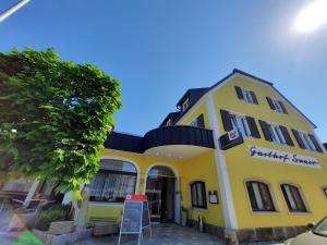 un bâtiment jaune avec un panneau devant lui dans l'établissement Gasthof Sauer GmbH, à Straß in Steiermark