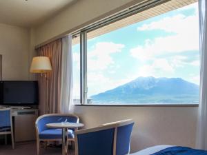 a room with a large window with a mountain view at HOTEL LiVEMAX BUDGET Kagoshima in Kagoshima