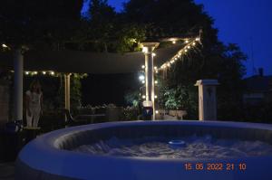 una bañera de hidromasaje en un patio por la noche con luces en Villa Dacia, en Guiglia