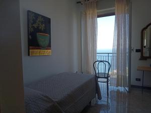 a bedroom with a bed and a chair and a window at Johnny and Mary's house breathtaking view locazioneturistica in Taormina