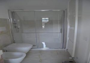 uma casa de banho com um WC e uma cabina de duche em vidro. em Locazione turistica Totaro em Vico del Gargano