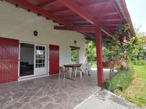 a patio with a red pergola and a table and chairs at Baketsua in Saint-Pée-sur-Nivelle