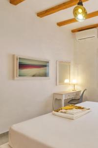 a white bedroom with a bed and a table at Eressian Lodgings, Skala Eressos Beach in Skala Eresou