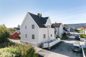 a white house with a car parked in a parking lot at Lys og sentral leilighet med terrasse og hage in Lillehammer