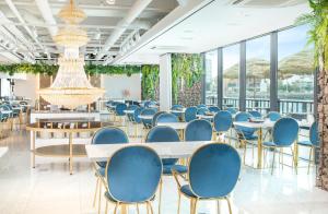 una sala da pranzo con sedie blu, tavoli e finestre di Utop Ubless Hotel Jeju a Jeju
