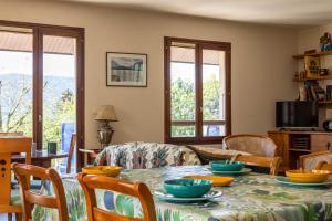 una sala da pranzo con tavolo, sedie e finestre di MAISON CHARLOTTE - Vue lac et à 5min des plages! a Veyrier-du-Lac