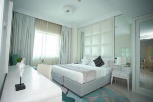 a white bedroom with a bed and a mirror at OSKENA Vacation Homes - Damac Maison Dubai Mall Street in Dubai