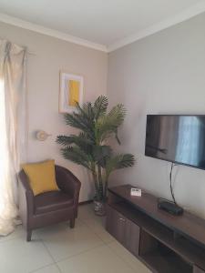 a living room with a chair and a flat screen tv at Tumi's Home away- 3 Bedroom in Witbank