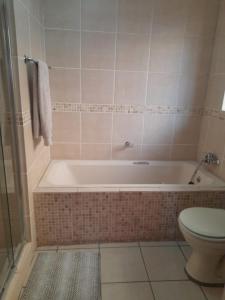 a bathroom with a bath tub and a toilet at Tumi's Home away- 3 Bedroom in Witbank