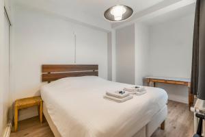 een slaapkamer met een wit bed en 2 handdoeken bij Retro woning te centrum Oostende, 5min van de kust in Oostende
