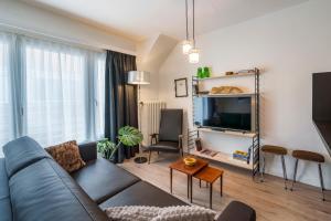 een woonkamer met een bank en een tv bij Retro woning te centrum Oostende, 5min van de kust in Oostende