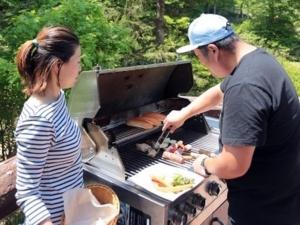 Un uomo e una donna che cucinano cibo su una griglia di Forest Inn Sangoro a Zaō Onsen