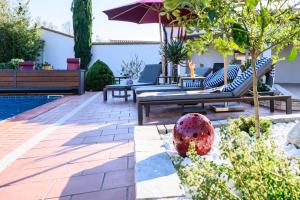 eine Terrasse mit einer Bank und einem Sonnenschirm neben einem Pool in der Unterkunft Gîtes La Catalane in Théza