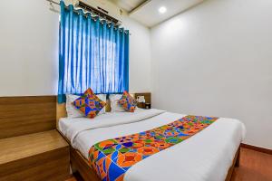 a bedroom with a large bed with a blue curtain at FabExpress Relax Inn in Sarkhej