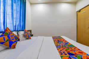1 dormitorio con 1 cama con un edredón colorido en FabExpress Relax Inn, en Sarkhej