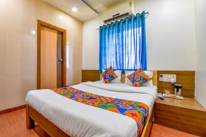 1 dormitorio con 1 cama grande y cortina azul en FabExpress Relax Inn, en Sarkhej