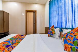 1 dormitorio con cama blanca y almohadas coloridas en FabExpress Relax Inn, en Sarkhej