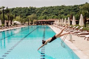 une femme plongeant dans une piscine d'un hôtel dans l'établissement Lopota Lake Resort & Spa, à Napareuli