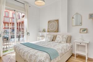 ein weißes Schlafzimmer mit einem Bett und einem Fenster in der Unterkunft Bright & Breezy MERCED in Málaga