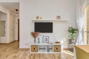 ein weißes Wohnzimmer mit einem TV an der Wand in der Unterkunft Bright & Breezy MERCED in Málaga