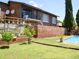a brick house with a swimming pool in front of it at Cosy - Best Rest Potch in Potchefstroom