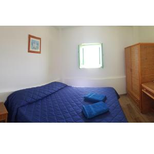 a bedroom with a bed with blue sheets and a window at Da Luciano in Stromboli