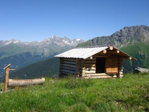 a log cabin on a hill with mountains in the background at Tgamon Somtgant mit Glasdach in Malmigiuer