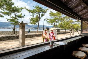 twee mensen in kostuums die voor een raam staan bij Kinsuikan in Miyajima
