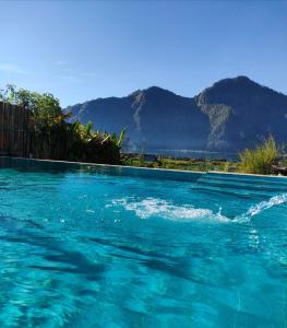 une piscine d'eau bleue et des montagnes en arrière-plan dans l'établissement Volcano Living, à Kintamani