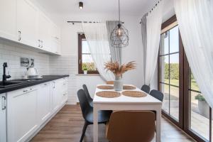 a white kitchen with a white table and chairs at Zielone Miejsce in Karwia