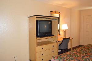 a hotel room with a television and a desk with a bed at Delux Inn Tulsa in Tulsa +7 photos
