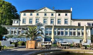 um grande edifício branco com mesas e cadeiras em frente em Hotel Meereswelle - Anno 1875 em Ahlbeck