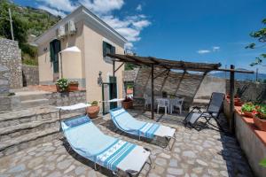 um pátio com 2 espreguiçadeiras, uma mesa e uma casa em La Sciuscella em Conca dei Marini