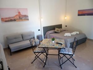 uma sala de estar com uma cama, uma mesa e cadeiras em Isole Dello Stagnone Apartaments em Birgi Vecchi