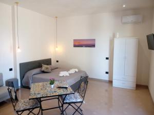 Isole Dello Stagnone Apartaments في بيرجي فيكي: غرفة نوم بسرير وطاولة مع كراسي