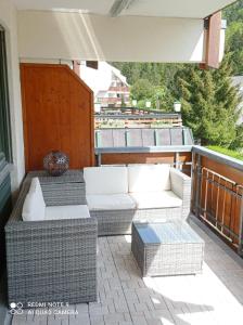 un patio con muebles de mimbre en el balcón en FeWo Tulipa Vera mit traumhafter Aussicht, en Todtmoos
