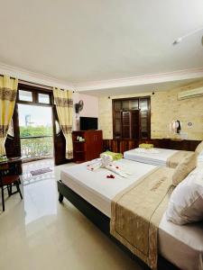 a bedroom with two beds and a desk and a window at Nam Phương Riverside Villa in Hue