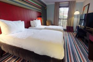 a hotel room with a large bed and a large window at Village Hotel Chester St David's in Garden City