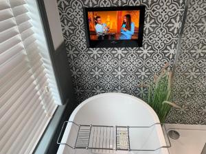 a bathroom with a toilet with a tv on the wall at Luxury House, central Stamford with parking in Stamford