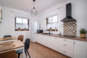 a kitchen with white cabinets and a table and a stove at Zielone Miejsce - w otoczeniu natury, z balią z jacuzzi opalaną drewnem in Karwia
