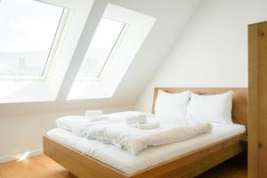 a bedroom with a bed with white sheets and windows at Nadland Apartments B61 in Vienna