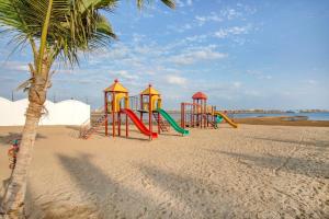 a playground on a beach with a palm tree at مراسي الأحلام لبيوت العطلات in Al Lith